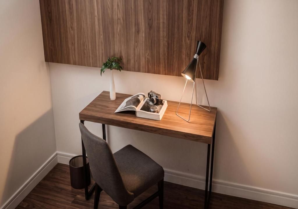 Un escritorio de madera con una lámpara, una silla y una pequeña planta.