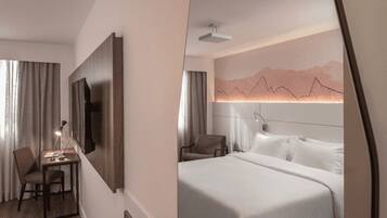 Habitación de hotel con escritorio, silla, cama y televisor de pared.