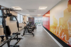 Ein Fitnessstudio mit Cardiogeräten, Krafttrainingsgeräten und einem großen Motivationsposter an der Wand.