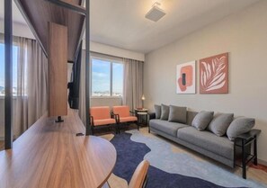A modern living room with a sofa, chairs, a dining table, and artwork on the wall. - Intercity Porto Alegre Cidade Baixa (Porto Alegre)