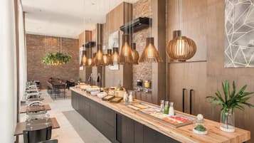 A modern kitchen with a long counter, hanging pendant lights, and a brick wall.