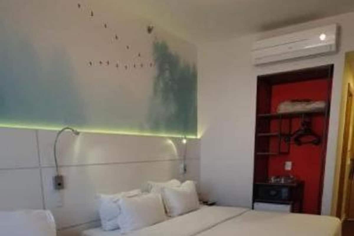 A hotel room with two beds, a red door, and a wall-mounted light fixture.