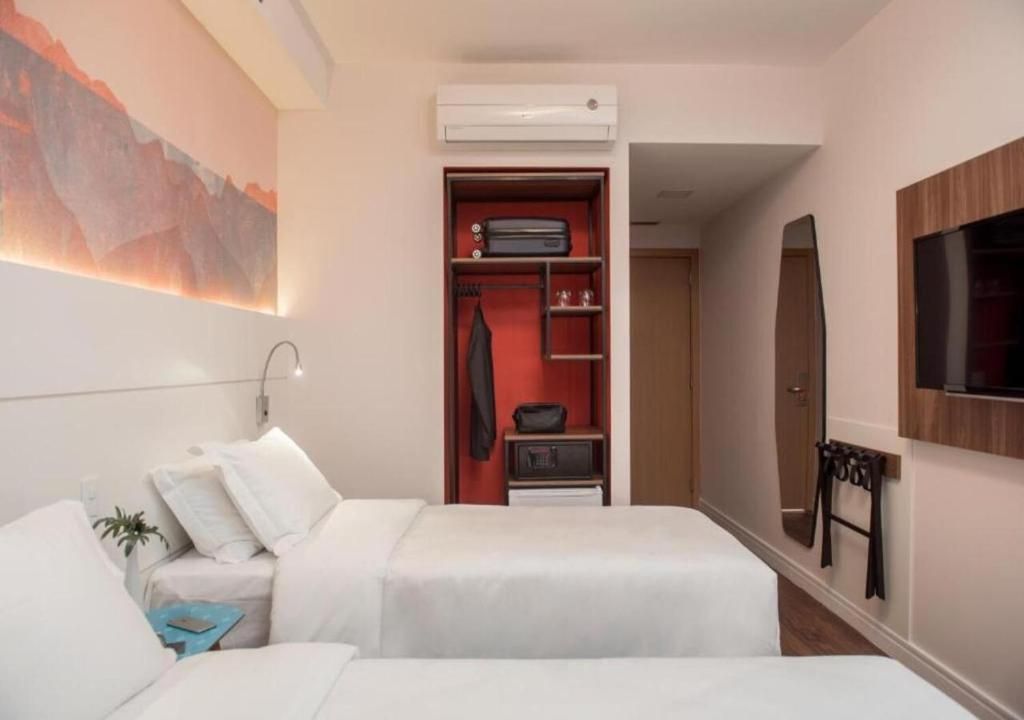 A hotel room with two beds, a wardrobe, a TV, and a painting on the wall.
