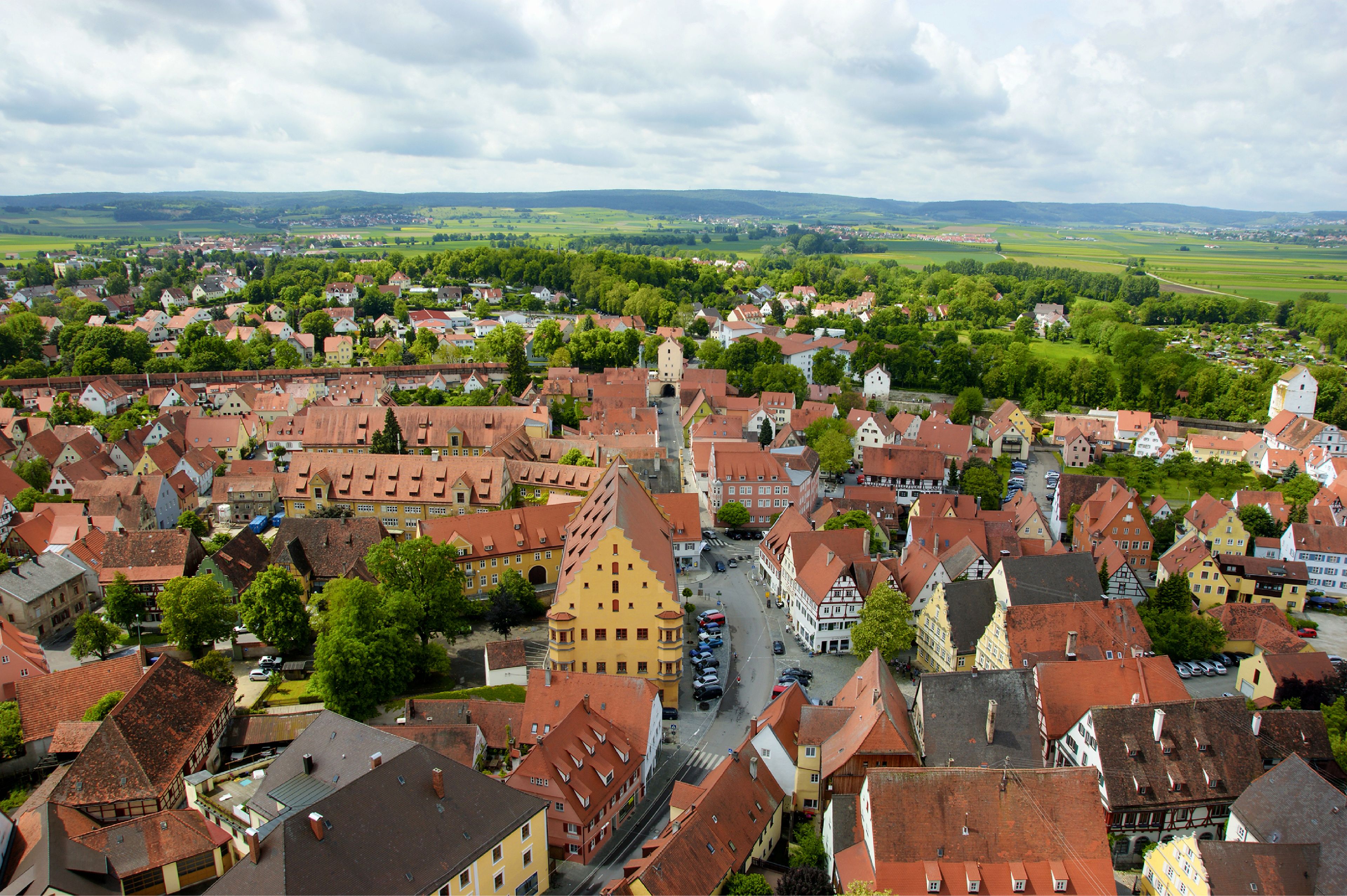 A town with historic buildings, a central street, and surrounding green fields.