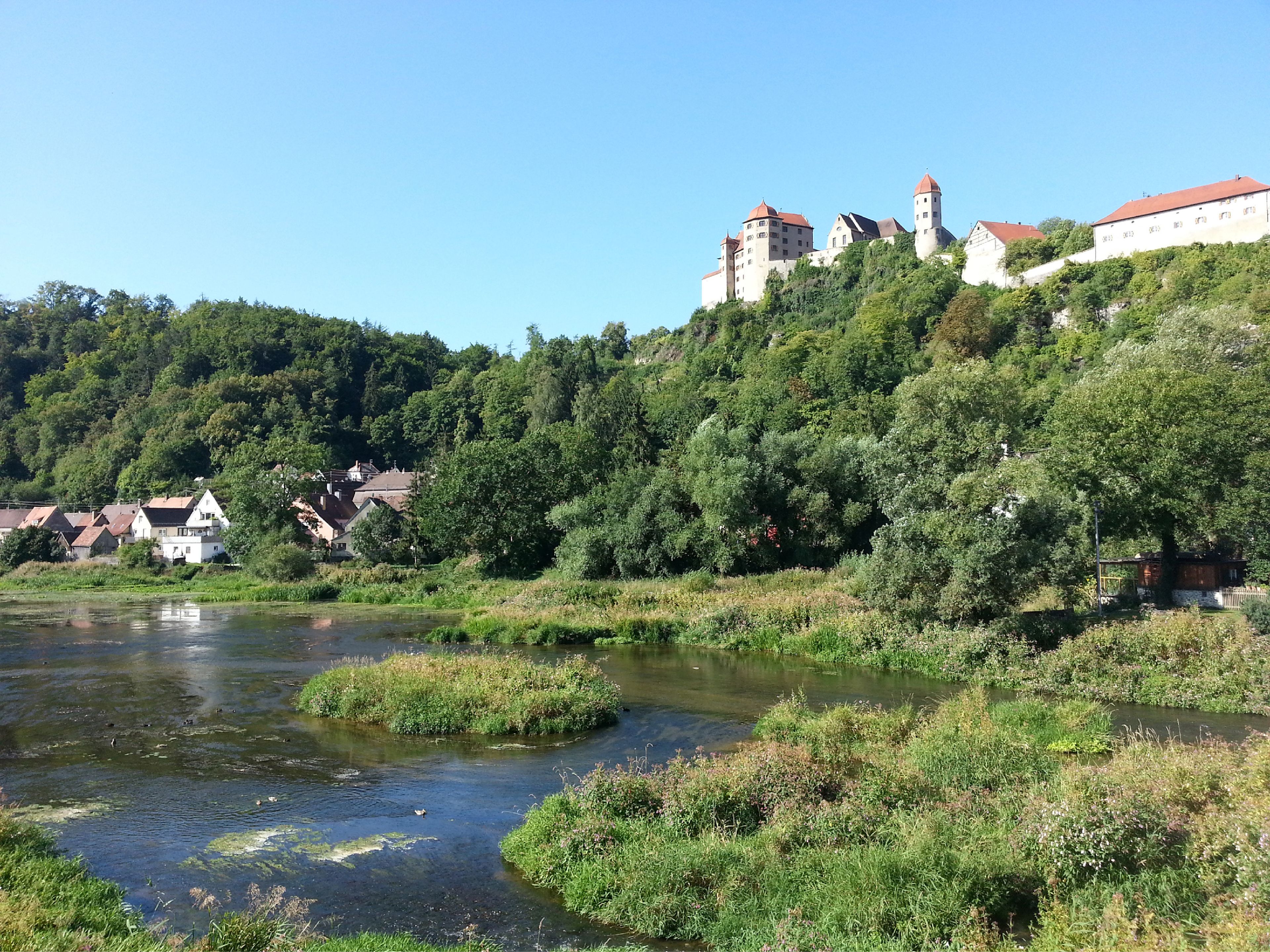 A castle on a hill with a river in the foreground.