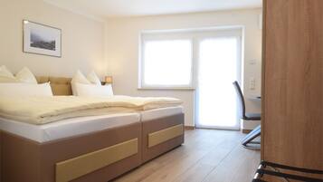 A bedroom with a bed, a chair, a desk, and a window.