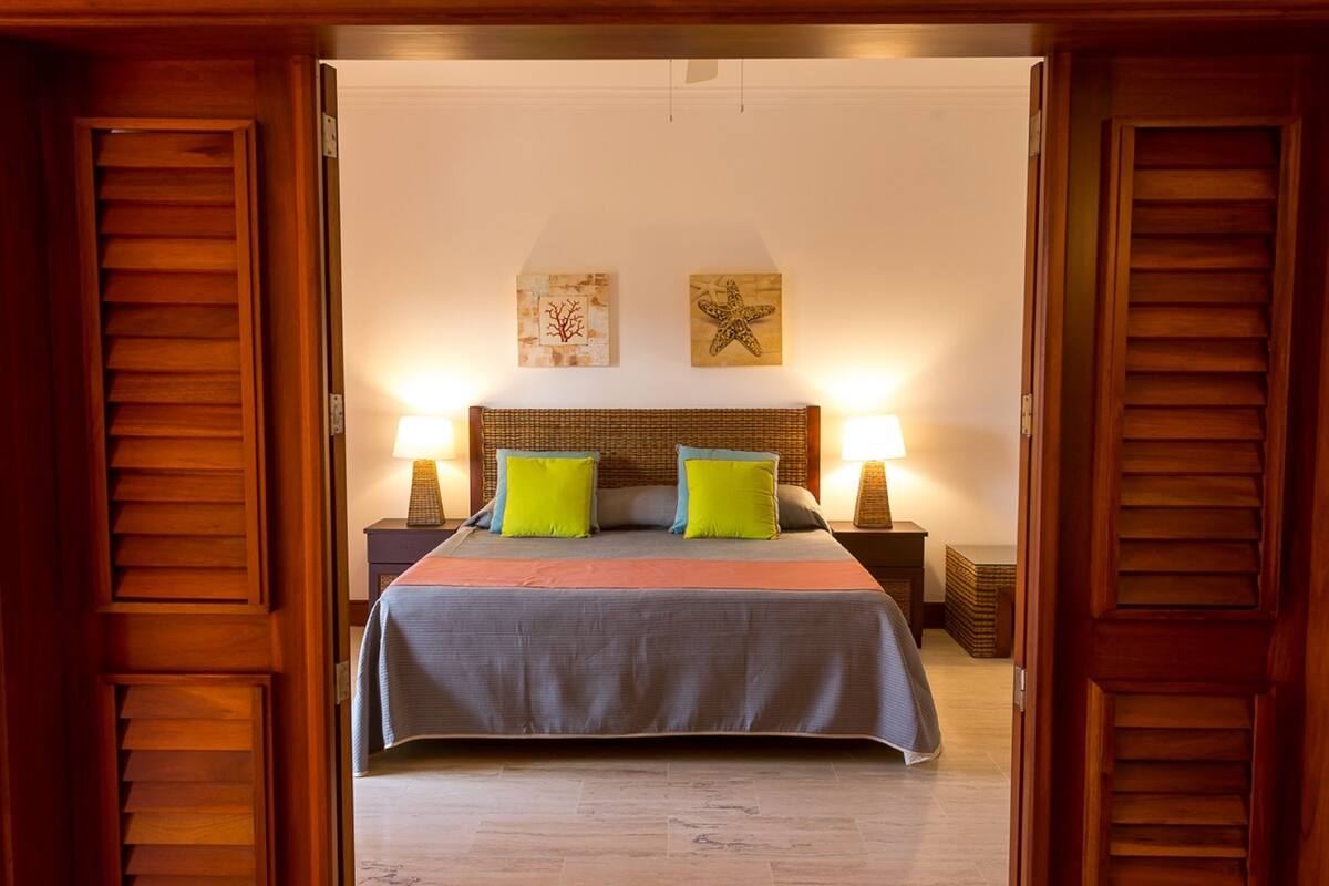 A hotel room with a large bed, two nightstands, a wooden headboard, and two wall art pieces.
