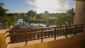 A balcony with a view of a golf course, a pond, and palm trees. - TOT Punta Cana Apartments (Punta Cana)