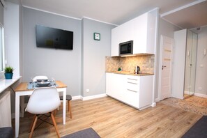 Una cocina compacta con microondas, una mesa de comedor con sillas y una pequeña planta en maceta.