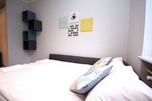 A neatly made bed with pillows, a wall with artwork, and a built-in shelf unit.