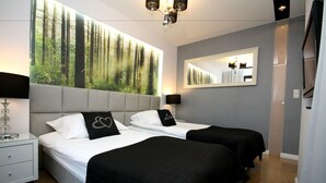A hotel room with two beds, a large mirror, a chandelier, and a forest-themed wall mural. - Rent a Flat apartments - Kilińskiego St. (Gdansk)