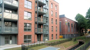 A multi-story building with a brick facade, large windows, and a courtyard with a basketball court. - Rent a Flat apartments - Kilińskiego St. (Gdansk)