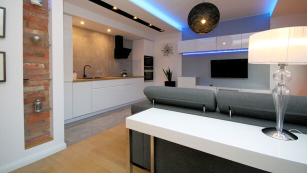 A modern kitchen with white cabinets, a built-in oven, and a grey countertop. - Rent a Flat apartments - Kilińskiego St. (Gdansk)