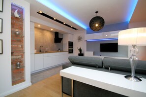 A modern kitchen with white cabinets, a built-in oven, and a grey countertop. - Rent a Flat apartments - Kilińskiego St. (Gdansk)