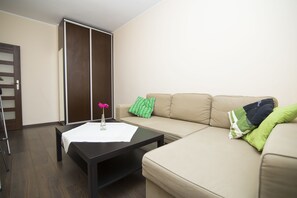 A living room with a sofa, a coffee table, and a sliding door closet. - Rent a Flat apartments - Korzenna St. (Gdansk)