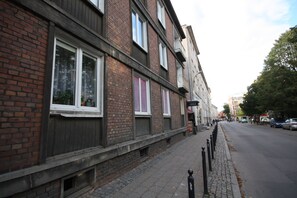 A row of brick buildings with large windows and a cobblestone sidewalk. - Rent a Flat apartments - Korzenna St. (Gdansk)