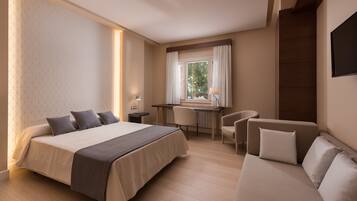 Una habitación de hotel con una cama grande, un escritorio, una silla y un sofá.