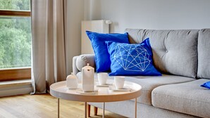 A modern living room with a grey sofa, blue pillows, a round coffee table, and a white radiator.