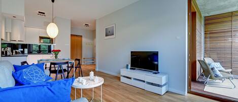 A modern living room with a sofa, TV, and dining area.