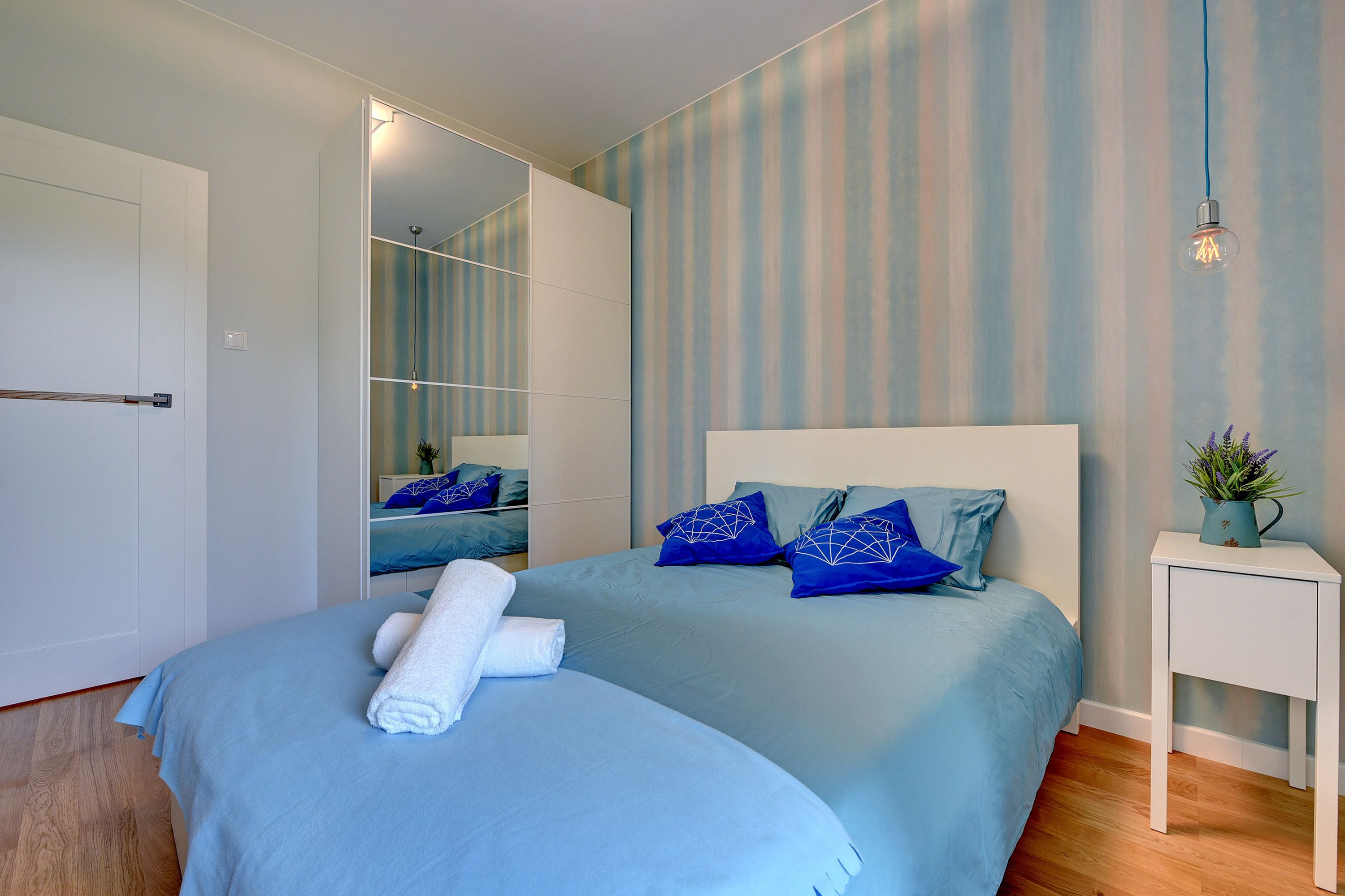 Une chambre à coucher moderne avec un grand lit, une table de chevet et un miroir.