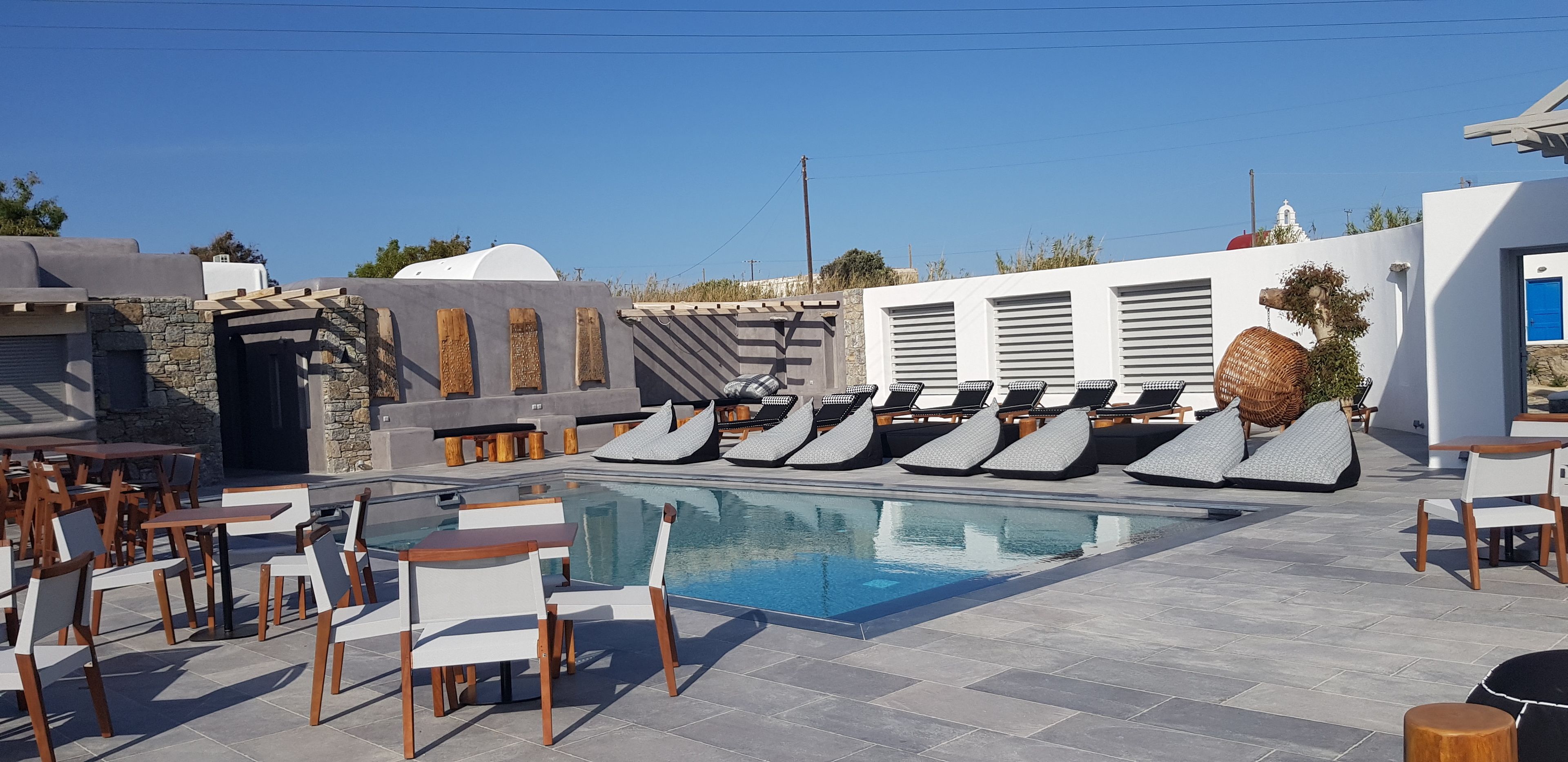 A poolside area with lounge chairs and tables, a clear pool, and a stone wall.