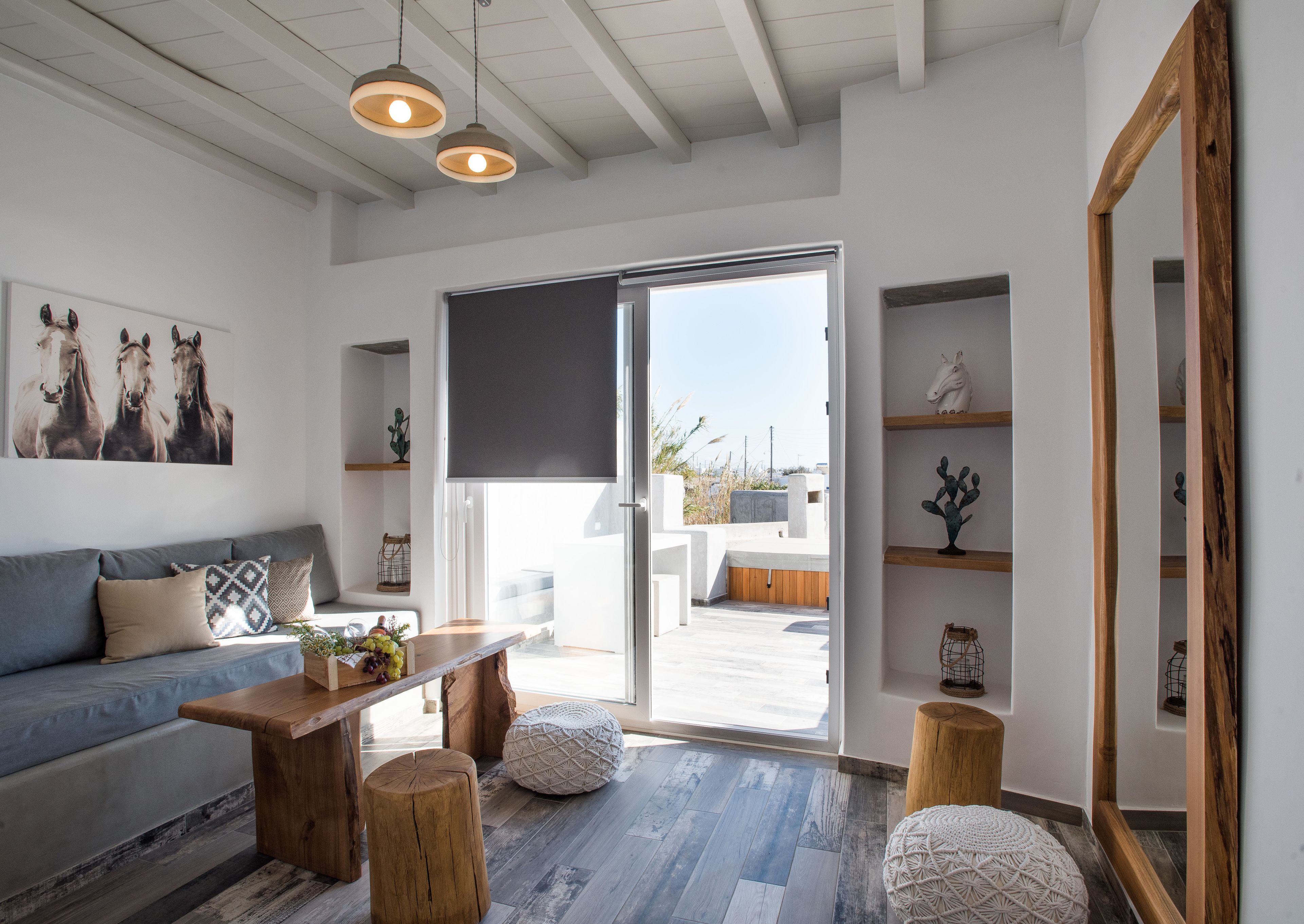 A modern living room with a sofa, coffee table, and wooden stools. There is a large window with a view of the outside.