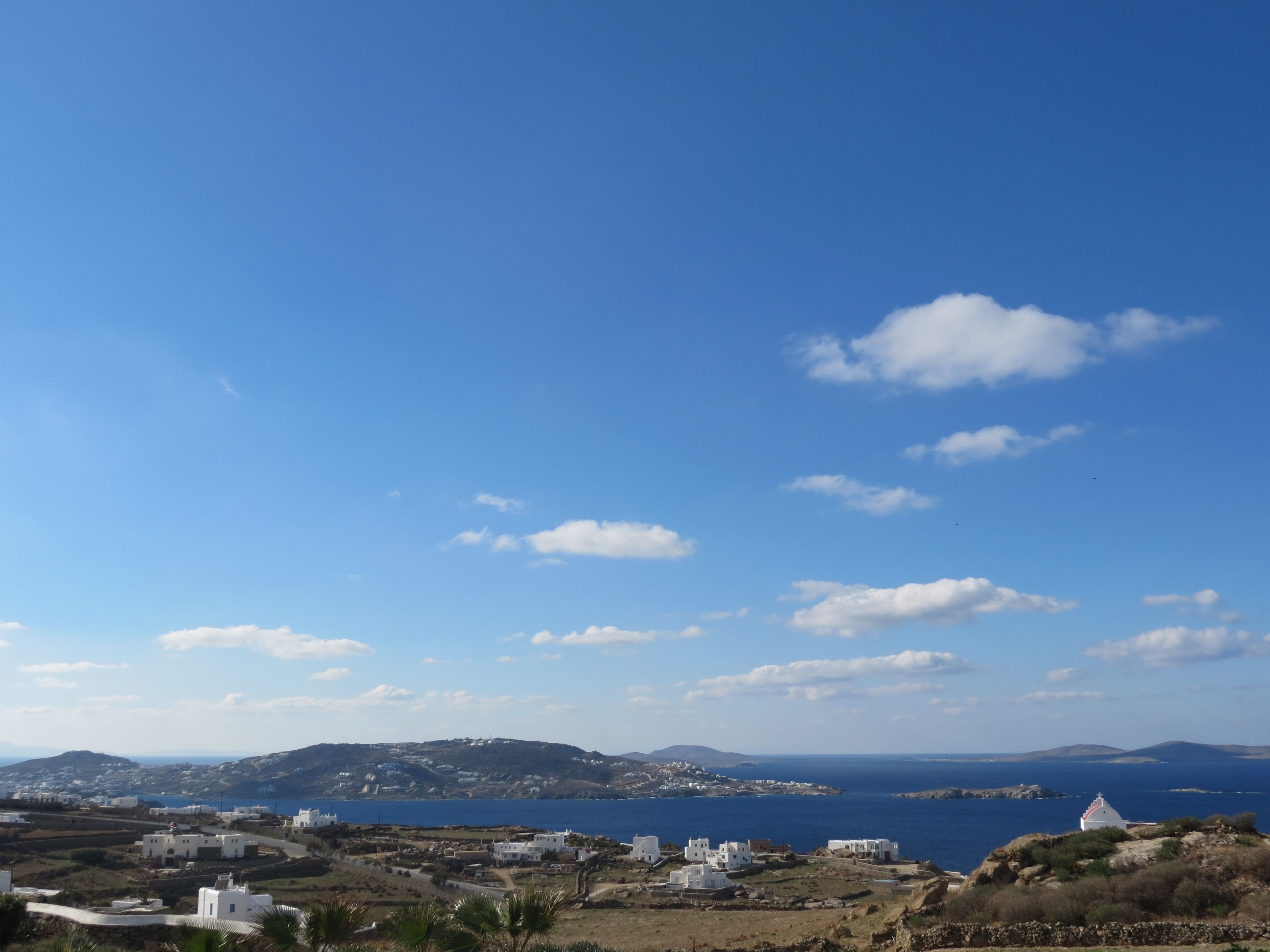 A coastal village with white buildings, a clear blue sky, and a view of the sea.