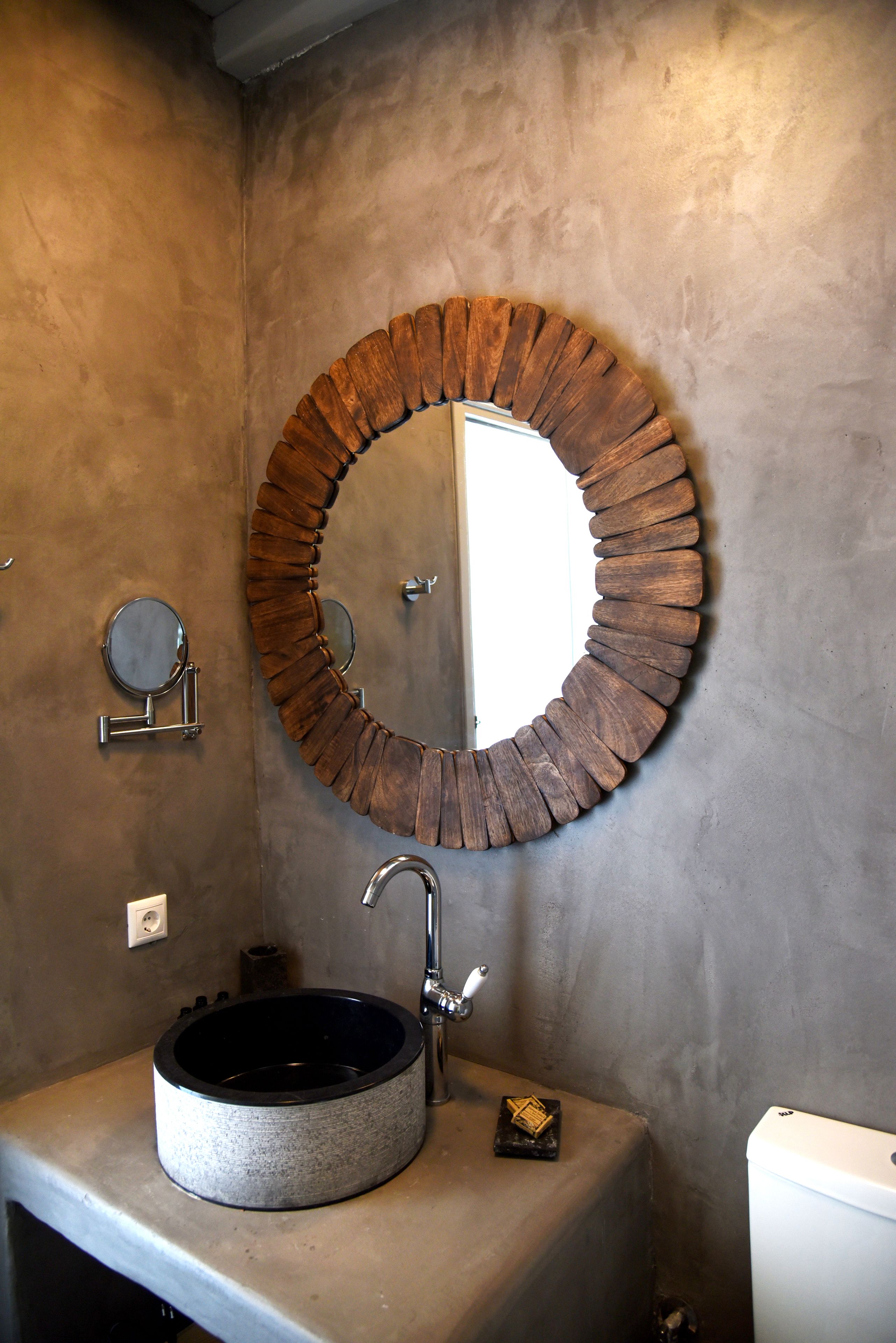 A bathroom with a round mirror, a sink, and a toilet.