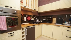 A kitchen with a refrigerator, oven, and stove. There are cabinets, a sink, and various kitchen utensils. - Rent a Flat apartments - Ogarna St. (Gdansk)