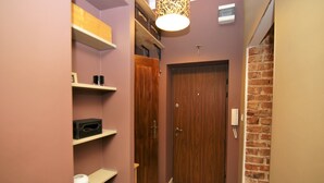 A hallway with wooden doors, shelves with various items, and a brick wall. - Rent a Flat apartments - Ogarna St. (Gdansk)