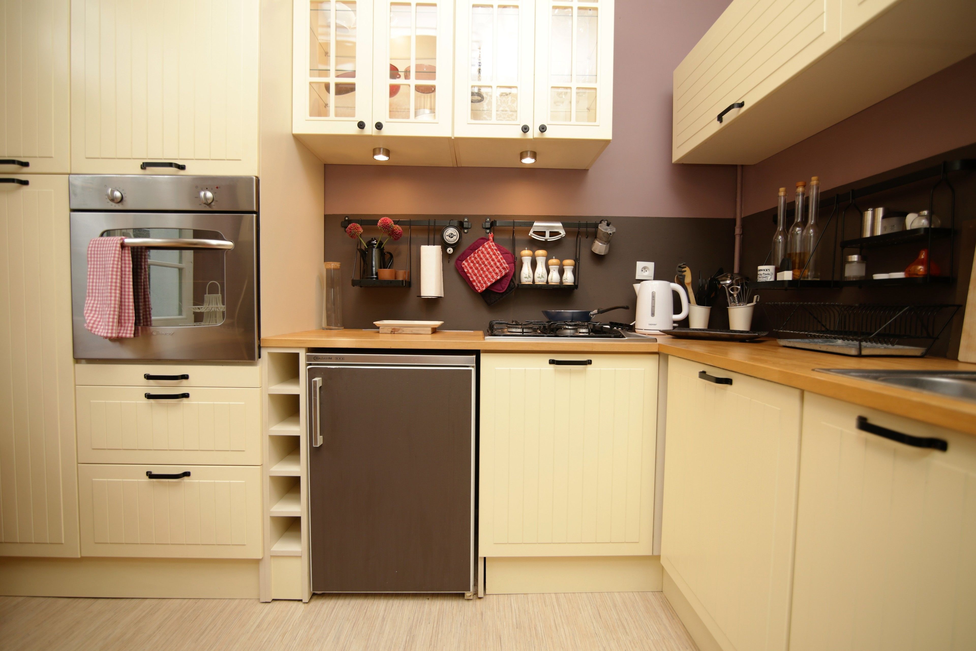 Una cocina compacta con horno empotrado, refrigerador y cafetera.
