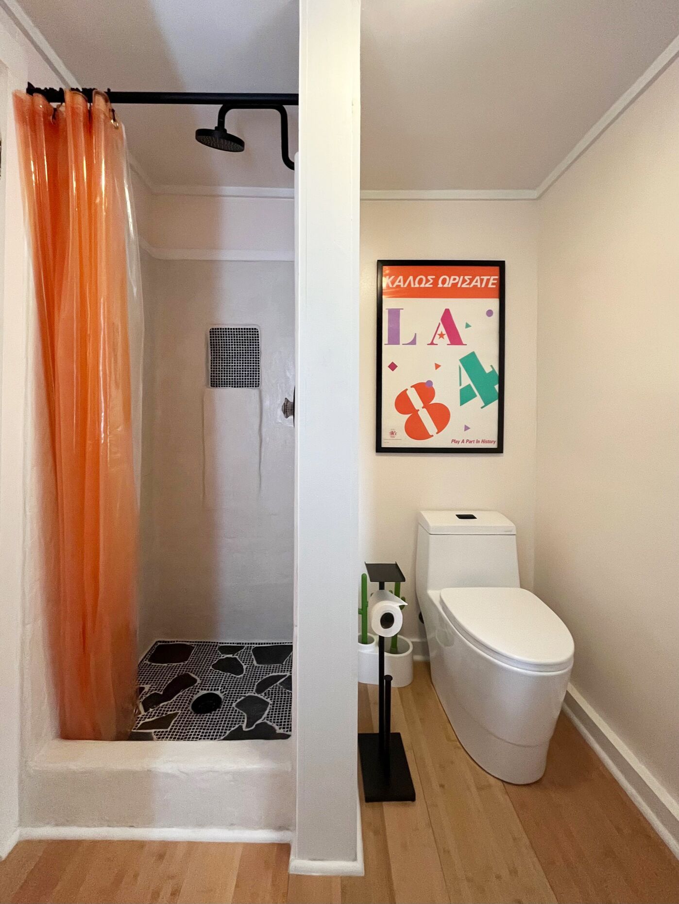 Un baño con ducha, inodoro y un cartel enmarcado en la pared.