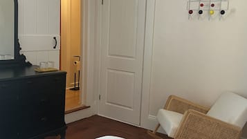 Un dormitorio con cama, cómoda, silla y puerta con interruptor de luz.