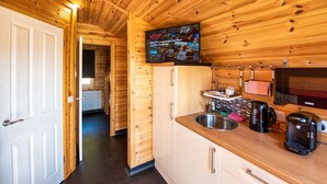 A wooden interior with a kitchen area, including a sink, coffee maker, and a television displaying Netflix. - Tigh an Each B&B & Laggan Glamping (Newtonmore)