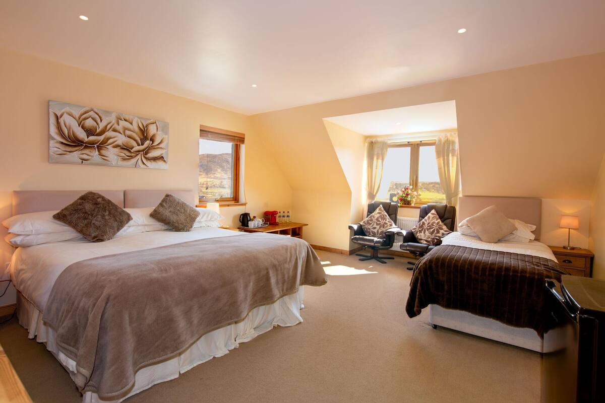 A hotel room with two beds, a desk, a chair, and a large window.