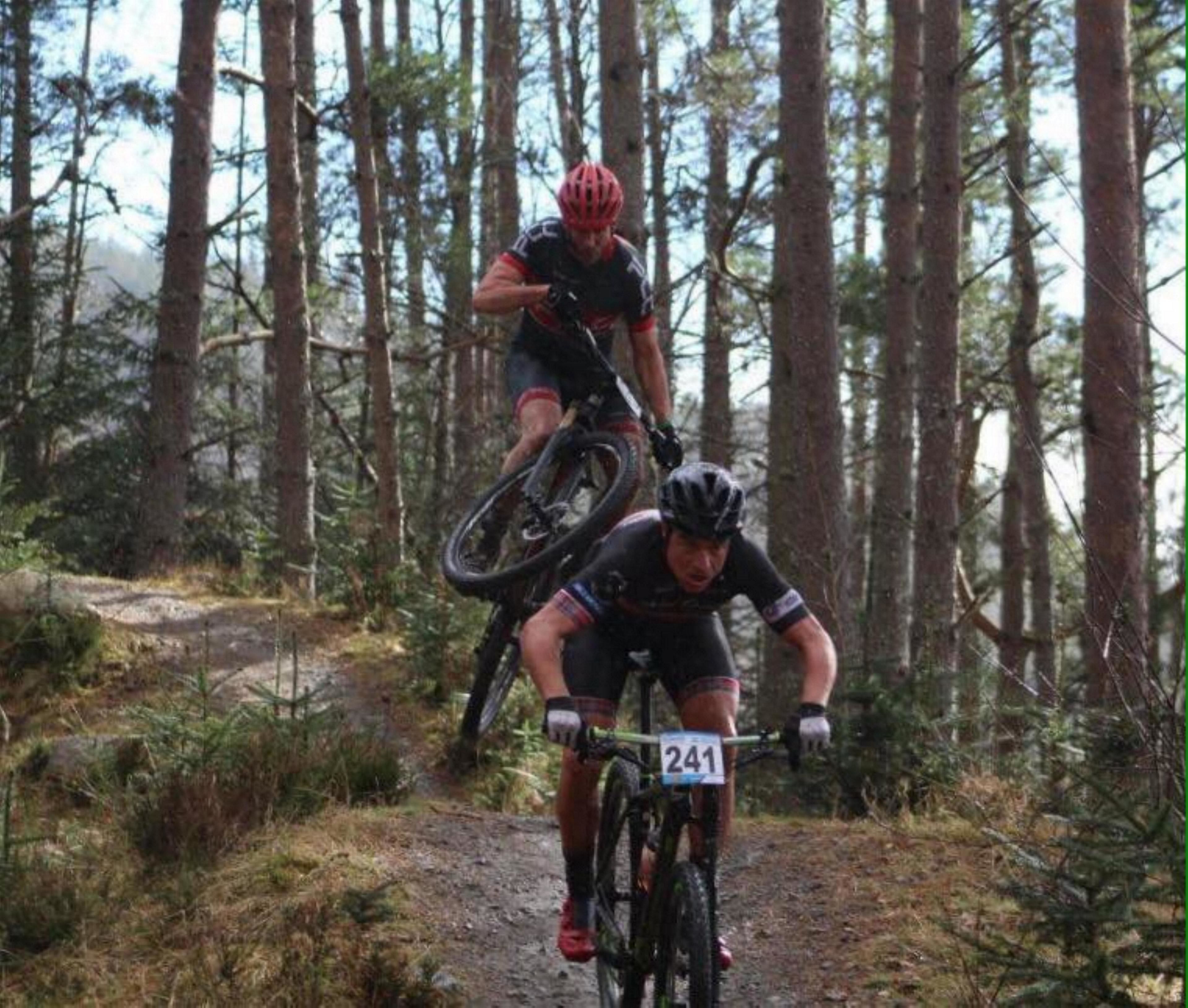 A forest trail with two cyclists.