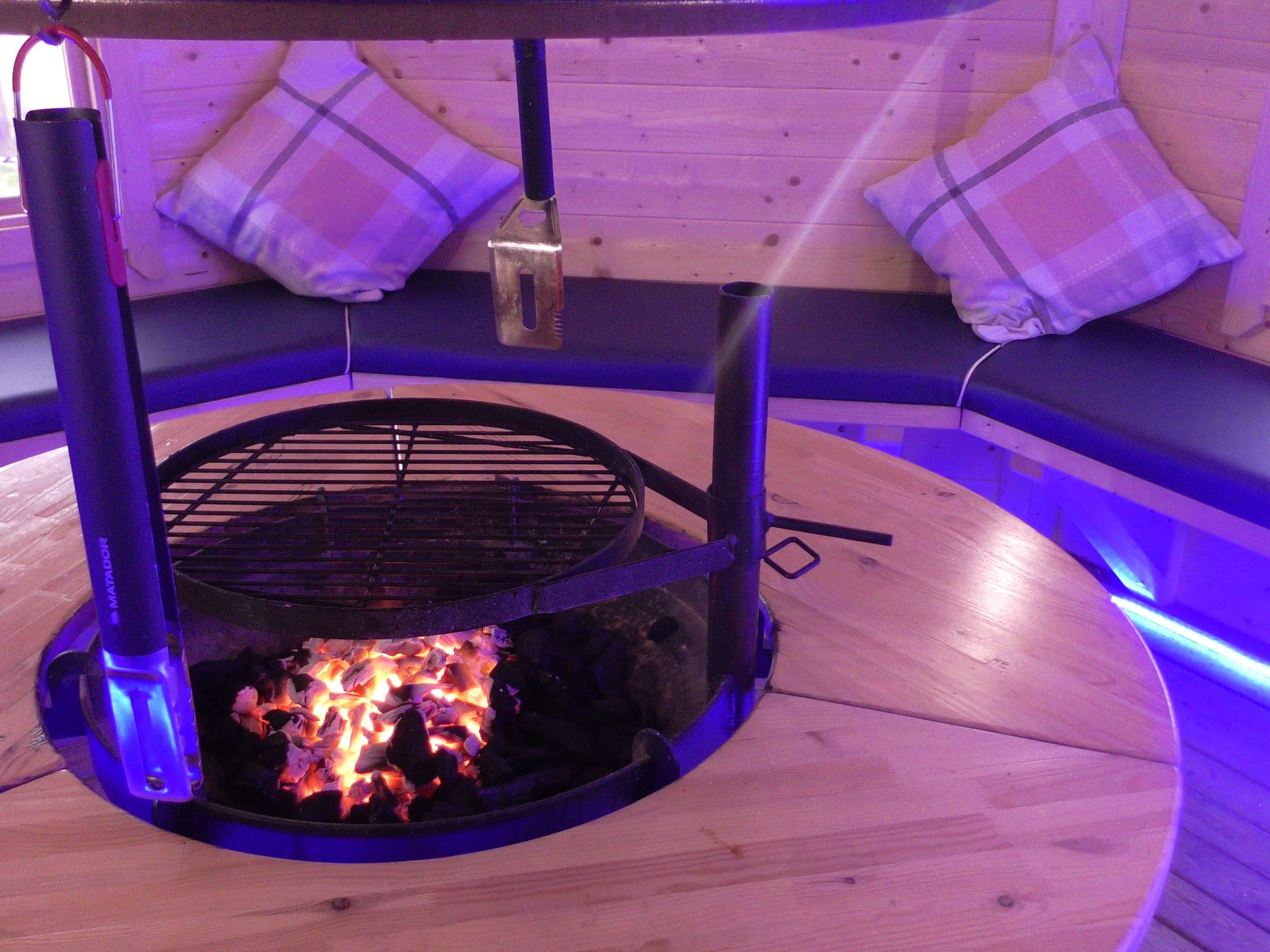 A circular wooden seating area with a built-in fire pit.