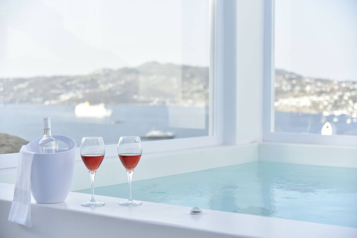 Zona de piscina con vista al mar y edificios a lo lejos.