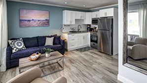 A modern living room with a sofa, coffee table, and a painting of a beach scene.