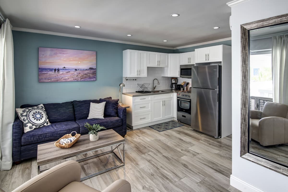 A modern living room with a sofa, coffee table, and a painting of a beach scene.
