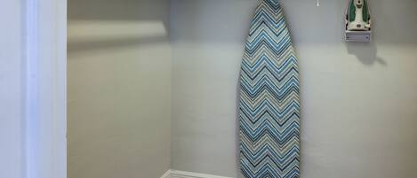 A corner of a room with a hanging iron and a towel rack.
