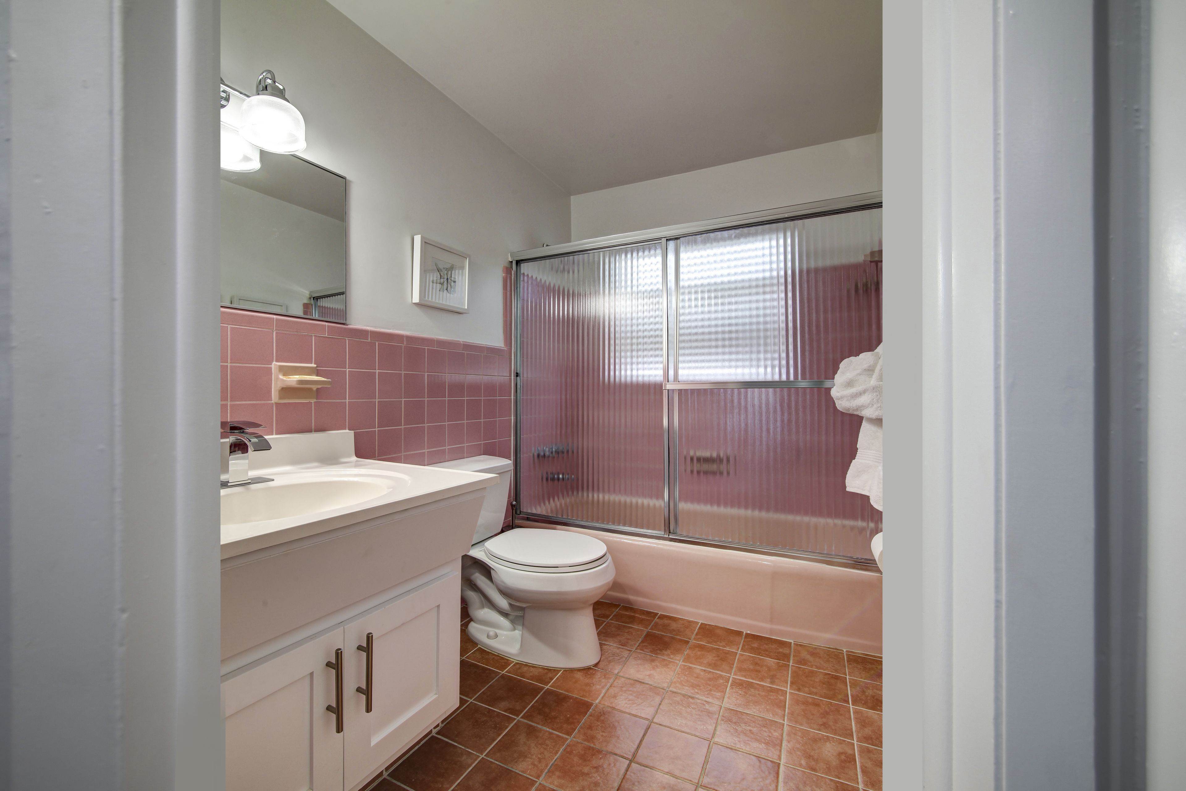 Un bany amb un lavabo, un moble de bany, un vàter i una cabina de dutxa de vidre.