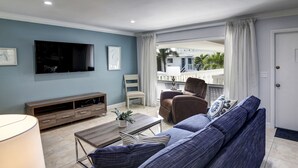 A living room with a sofa, TV, and a balcony with curtains.