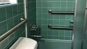 Un bagno con una vasca da bagno bianca, un water bianco e una doccia con porta in vetro. Sono presenti due maniglie metalliche per la sicurezza.