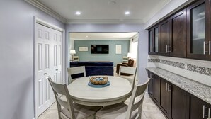 A dining area with a round table, four chairs, and a blue sofa in the background.