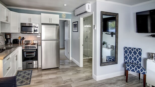 A modern kitchen with white cabinets, stainless steel appliances, and a patterned rug.