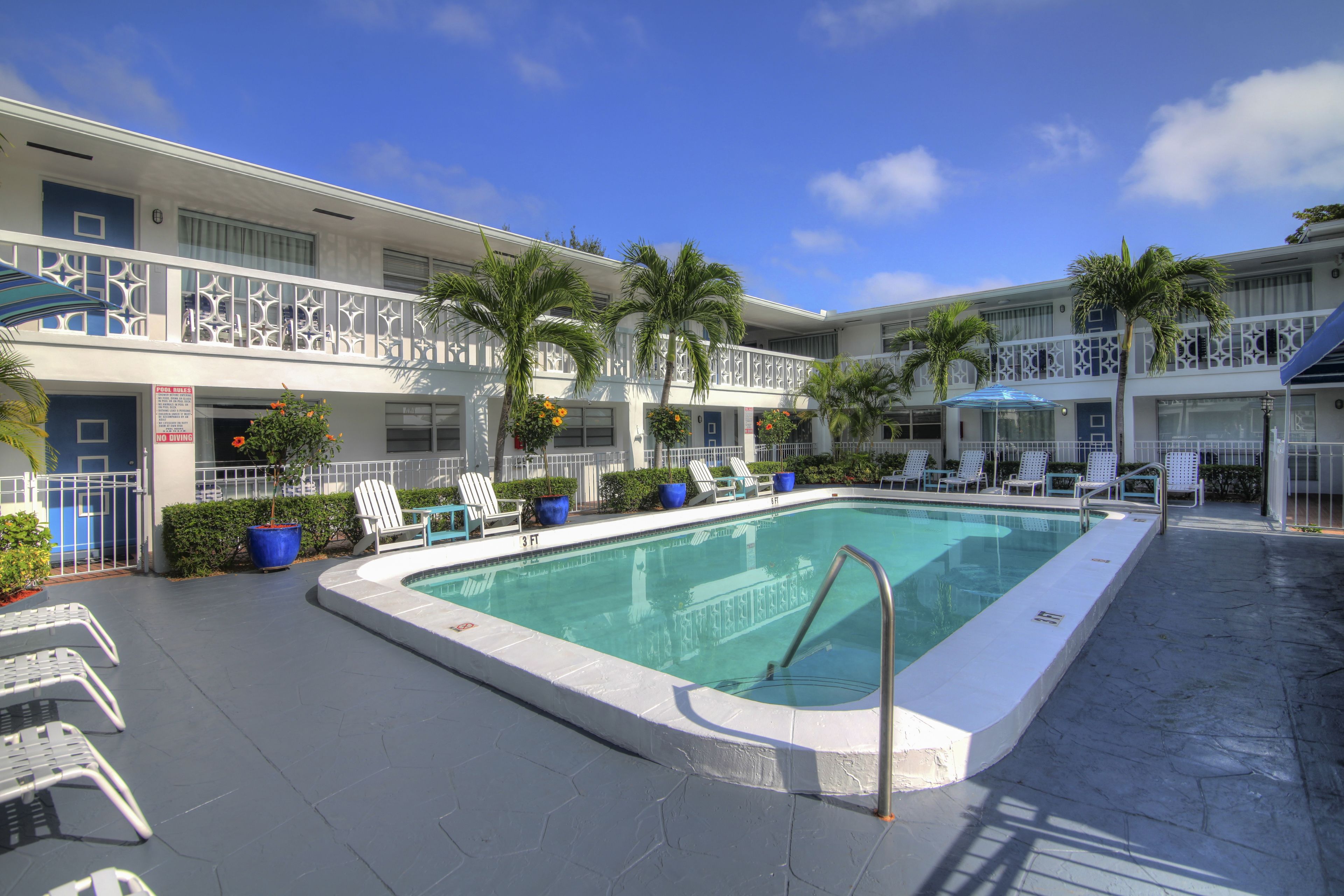 A pool area with lounge chairs and palm trees.