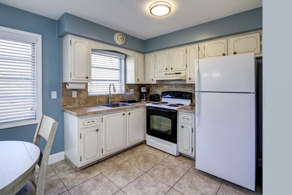 A kitchen with white cabinets, a stove, oven, and a refrigerator.