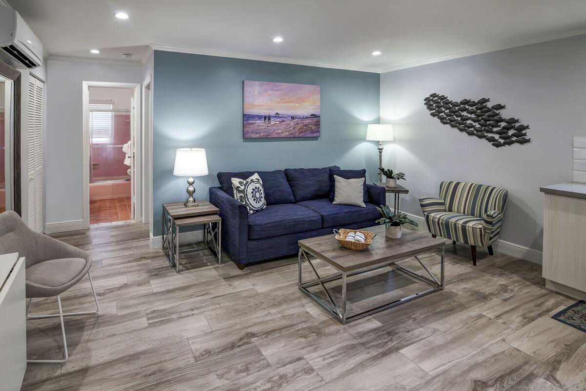 A modern living room with a blue sofa, striped armchair, and a coffee table.