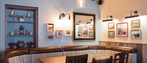 A cozy restaurant with a wooden bench seating area, a wooden table, and wall-mounted picture frames.